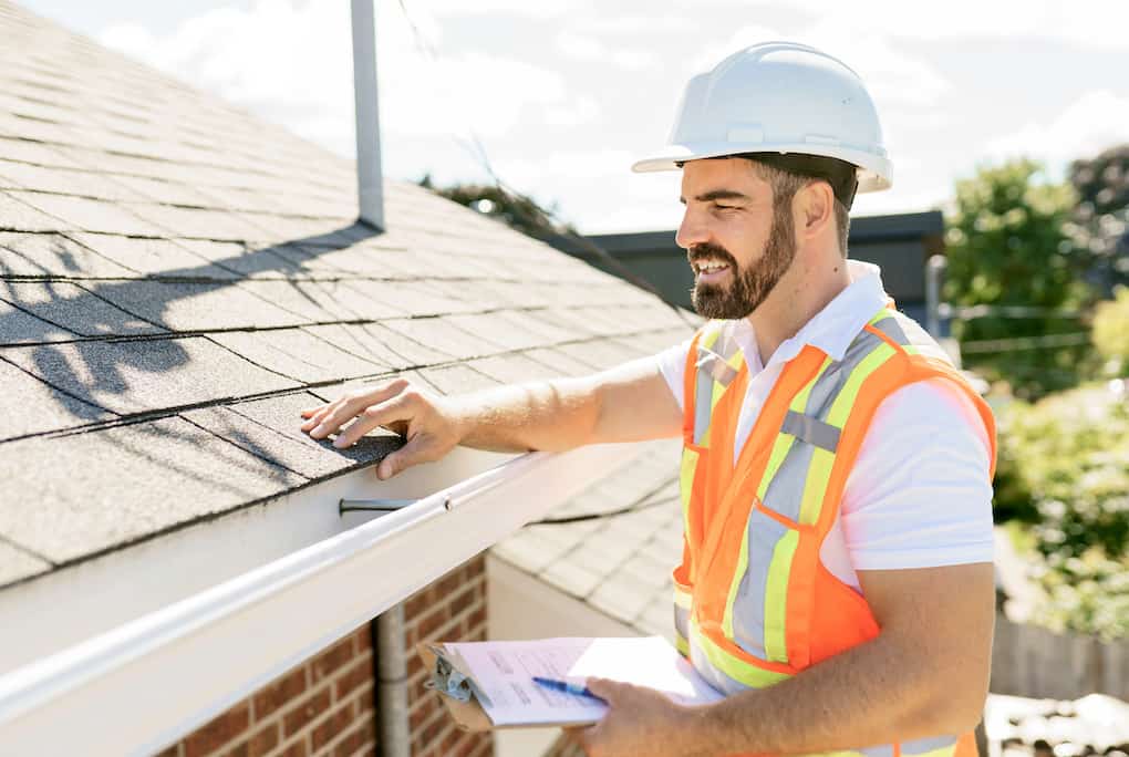 man in hardhat holding clipboard looking at roof; roof referral program